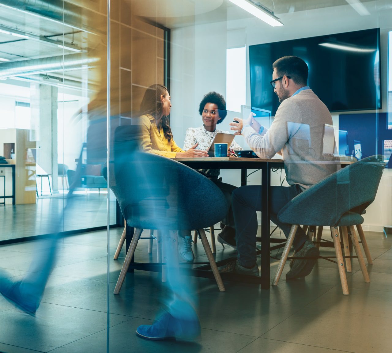 Three team members sitting in an office at a table having a happy discussion.